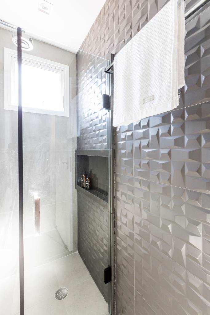 banheiro bege com revestimento 3d na parede do chuveiro